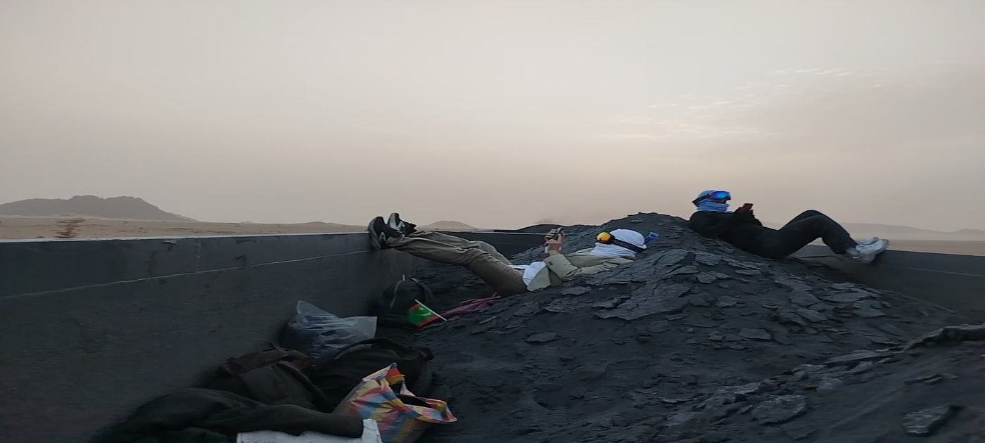 Travellers on top of the loaded iron ore train in the Sahara