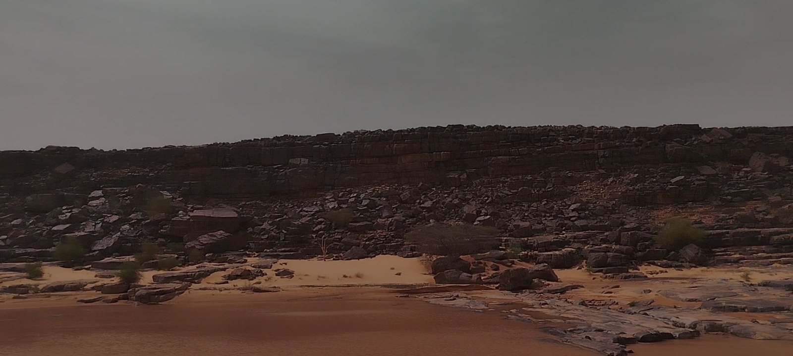 Rocky Adrar plateau and desert sand under a dramatic sky in Mauritania